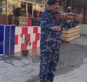 في صورة فريدة وباهرة.. شرطي عراقي يعزف على آلة الكمان في أحد اسواق الحلة، وينال التصفيق